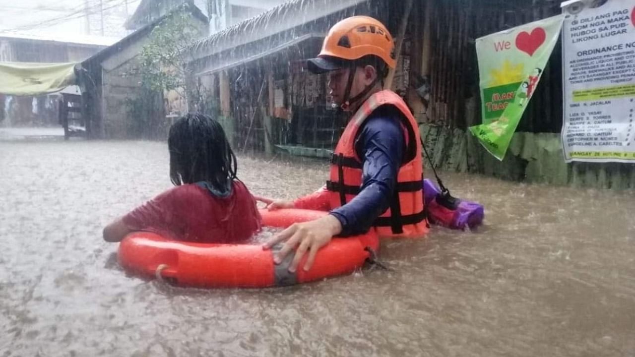 A Philippine Coast Guard personnel assists a resident in their evacuation due to flooding caused by Typhoon Rai in Cagayan De Oro City, Philippines. Credit: Reuters Photo