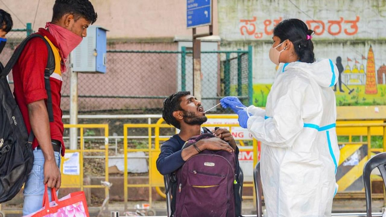 A health worker collects swab sample of a commuter for Covid-19 test, amid fear of the spreading of a new variant of Covid-19, at KSR railway station in Bengaluru, Saturday, Dec. 4, 2021. Credit: PTI Photo