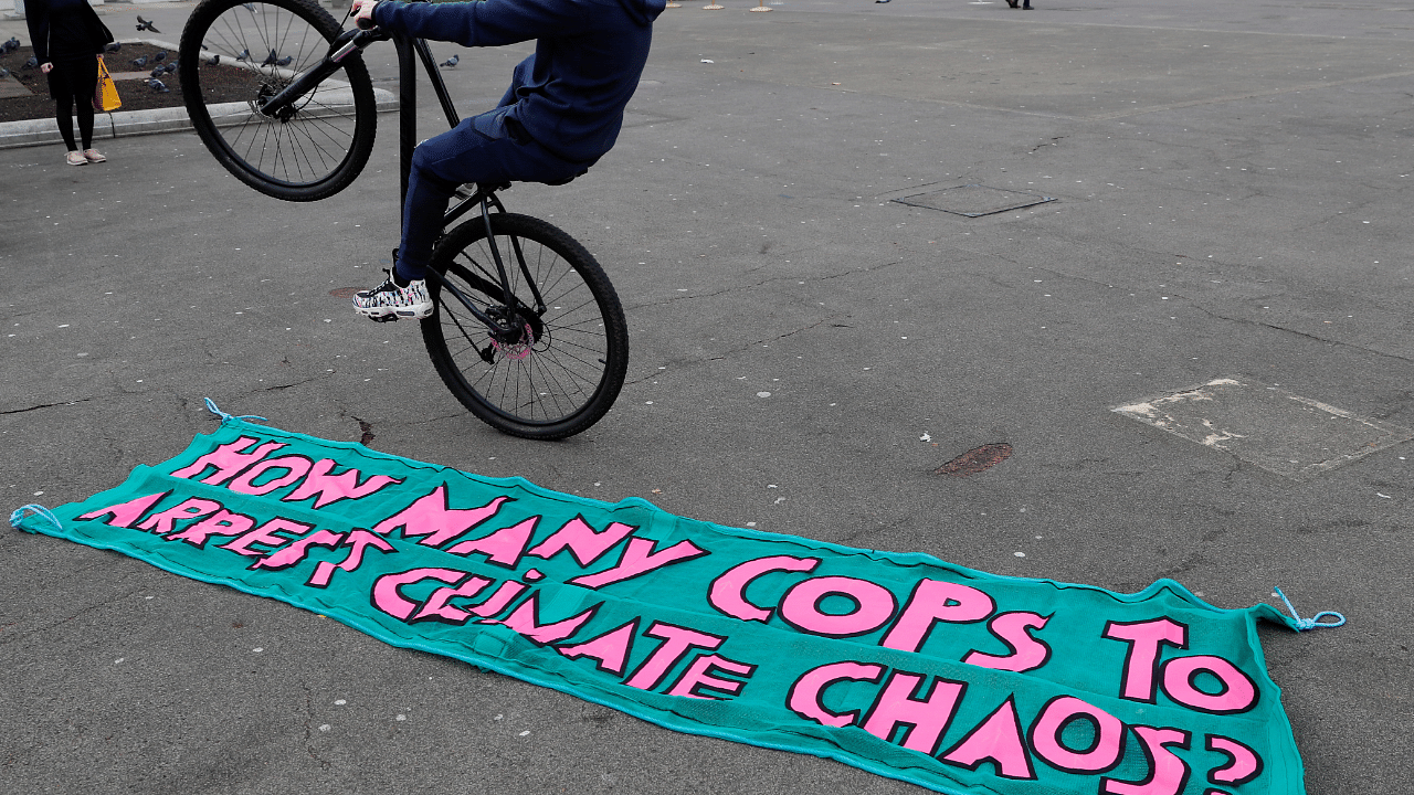 A man rides a bicycle in front of a banner lying on the ground in George Square, as the UN Climate Change Conference (COP26) takes place in Glasgow. Credit: Reuters Photo