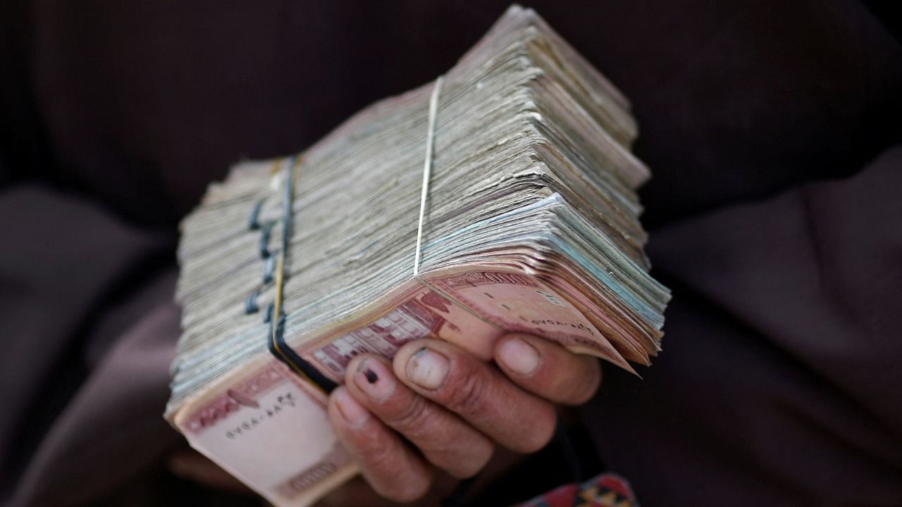 A money changer holds a stack of Afghan currency on a street in central Kabul. Credit: Reuters File Photo
