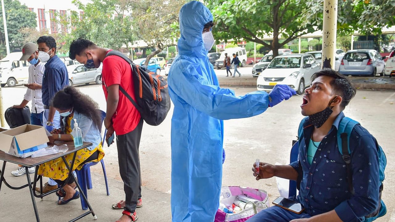 A health worker conducts Covid-19 testing of commuters amid fear of spread of the Omicron variant, in Bengaluru. Credit: PTI file photo