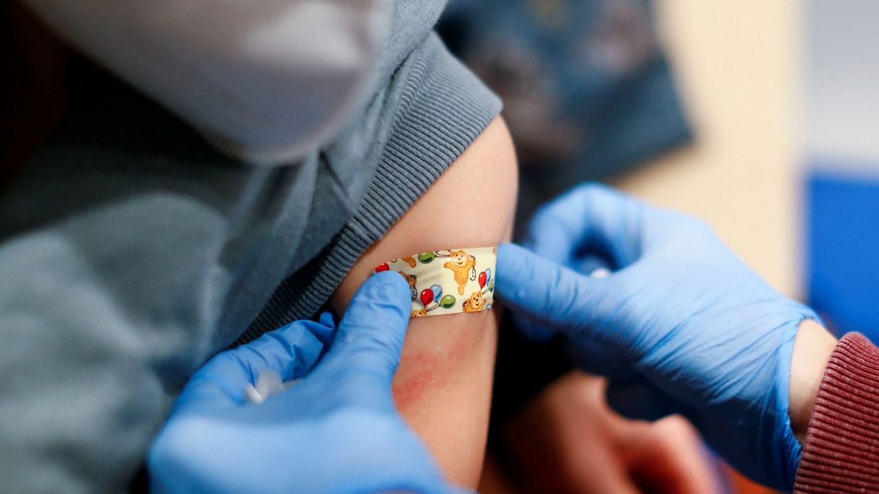 A boy receives a band-aid after getting a dose of the Pfizer-BioNTech vaccine for children against the coronavirus during a vaccination event for children at the Lanxess Arena in Cologne, Germany, December 18, 2021. Credit: Reuters File Photo