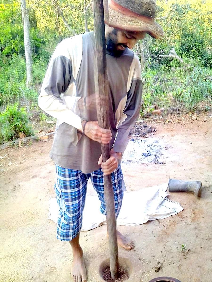 Abhishek Gatty dehusks paddy with a pestle.