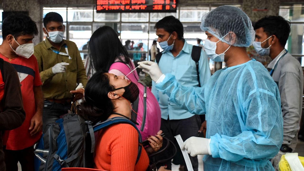 A healthcare worker collects a swab sample of a passenger for Covid-19 test, at Bandra Terminal, in Mumbai. Credit: PTI File Photo