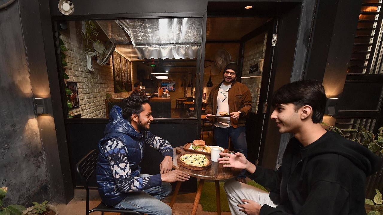 Owner of Ebony Cafe Saddam Khan interacts with customers at his cafe near Jama Masjid. Credit: PTI Photo