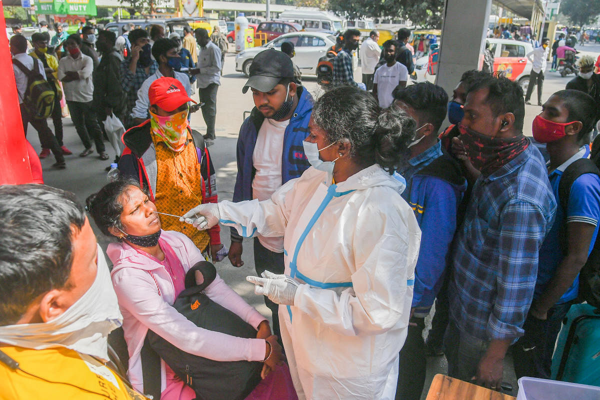 A health worker collects samples for Covid test at KSR Railway Station in Bengaluru on Sunday. Credit: DH Photo/S K Dinesh