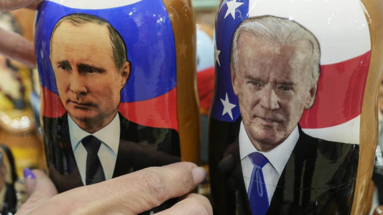 A customer shows to photographer a traditional Russian wooden dolls called Matreska of Russian President Vladimir Putin, center, and U.S. President Joe Biden, center right, at a souvenirs store in Moscow, Russia. Credit: AP Photo