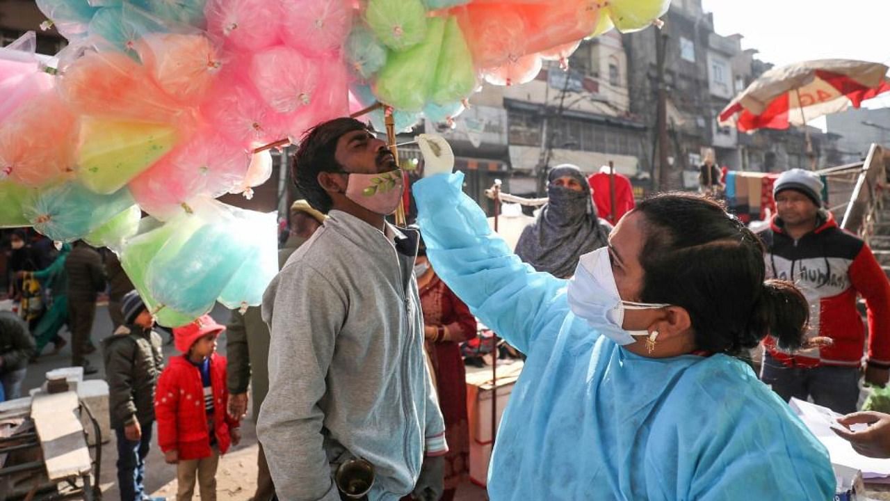A health worker collects swab sample of a vendor for Covid-19 test, in wake of recent surge in coronavirus cases, in Jammu, Sunday, Dec. 19, 2021. Credit: PTI Photo