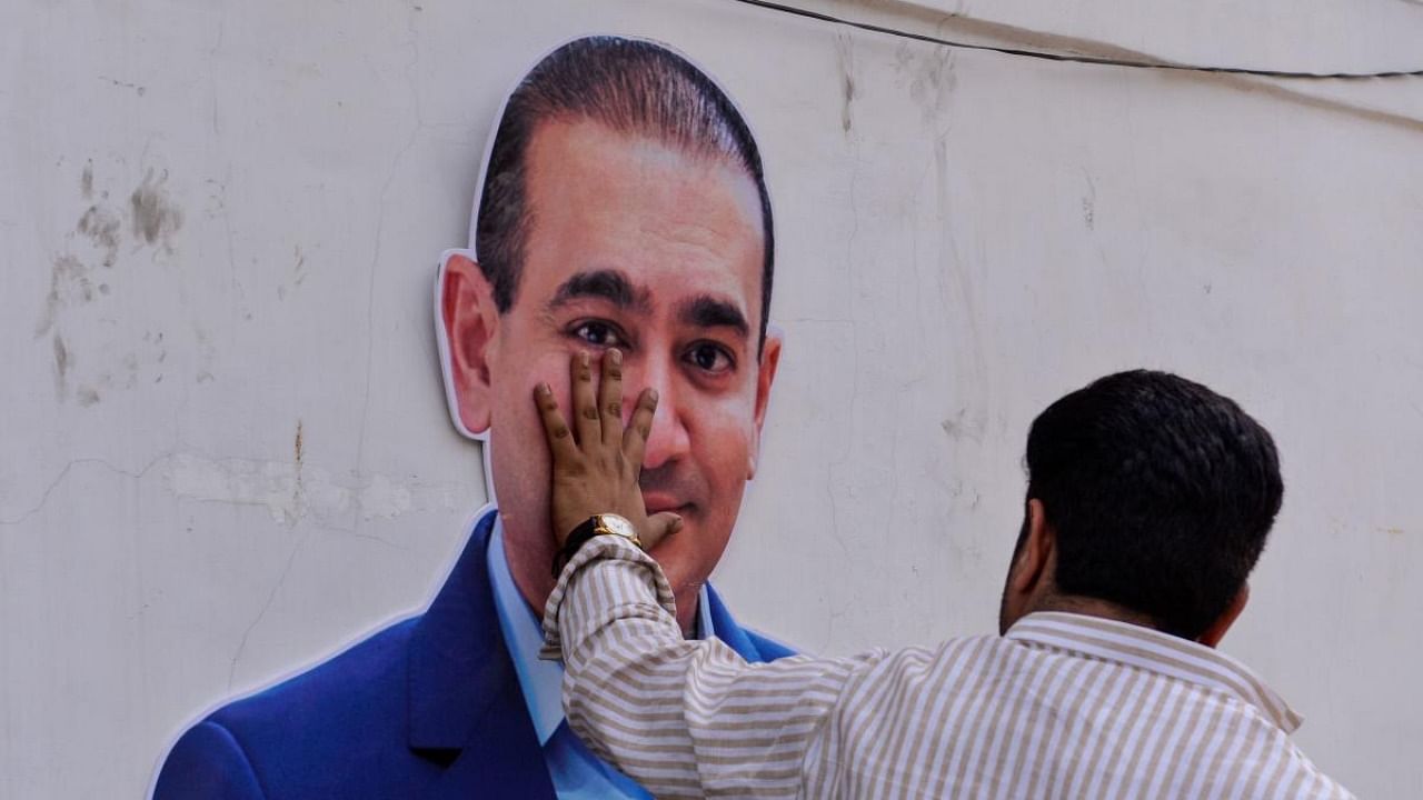 In this file photo taken on February 16, 2018 An Indian supporters of the Congress Party keeps his hand on the face of a cut out of billionaire jeweller Nirav Modi during a protest in New Delhi. Credit: AFP Photo