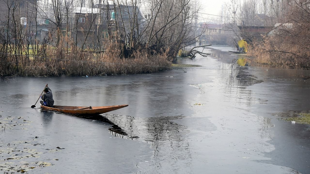 A boatman wades through a frozen surface of Dal Lake during a cold winter morning, in Srinagar, Sunday, December 19, 2021. Credit: PTI File Photo