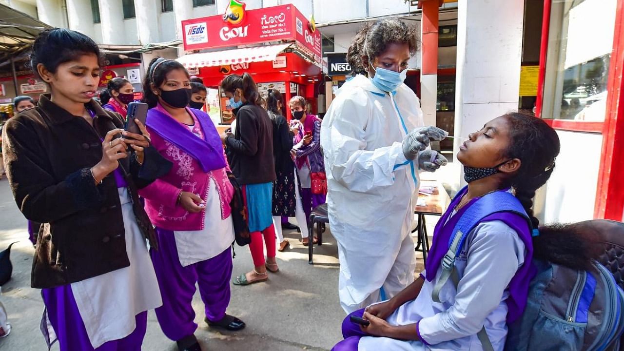 A health worker conducts Covid-19 testing of commuters as Omicron cases cases rise in India, at KSR railway station in Bengaluru. Credit: PTI Photo