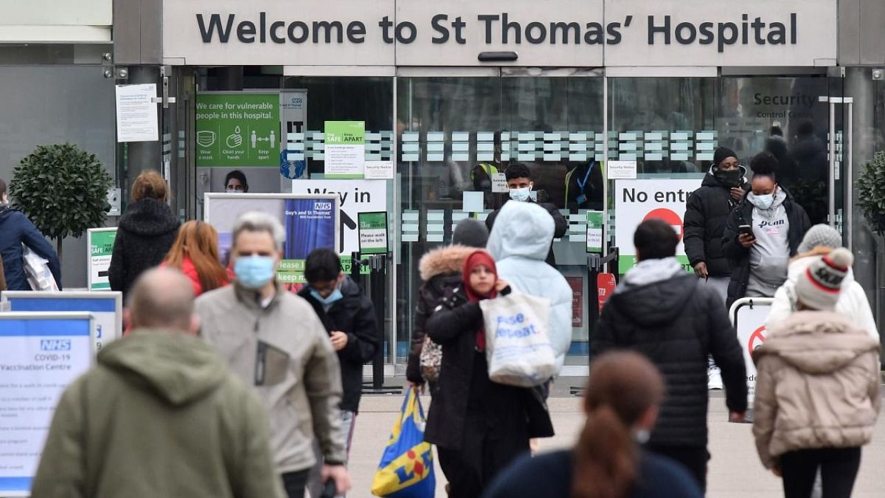 People, some wearing face coverings to combat the spread of Covid-19, arrive at, and depart from, St Thomas' hospital in central London. Credit: AFP photo