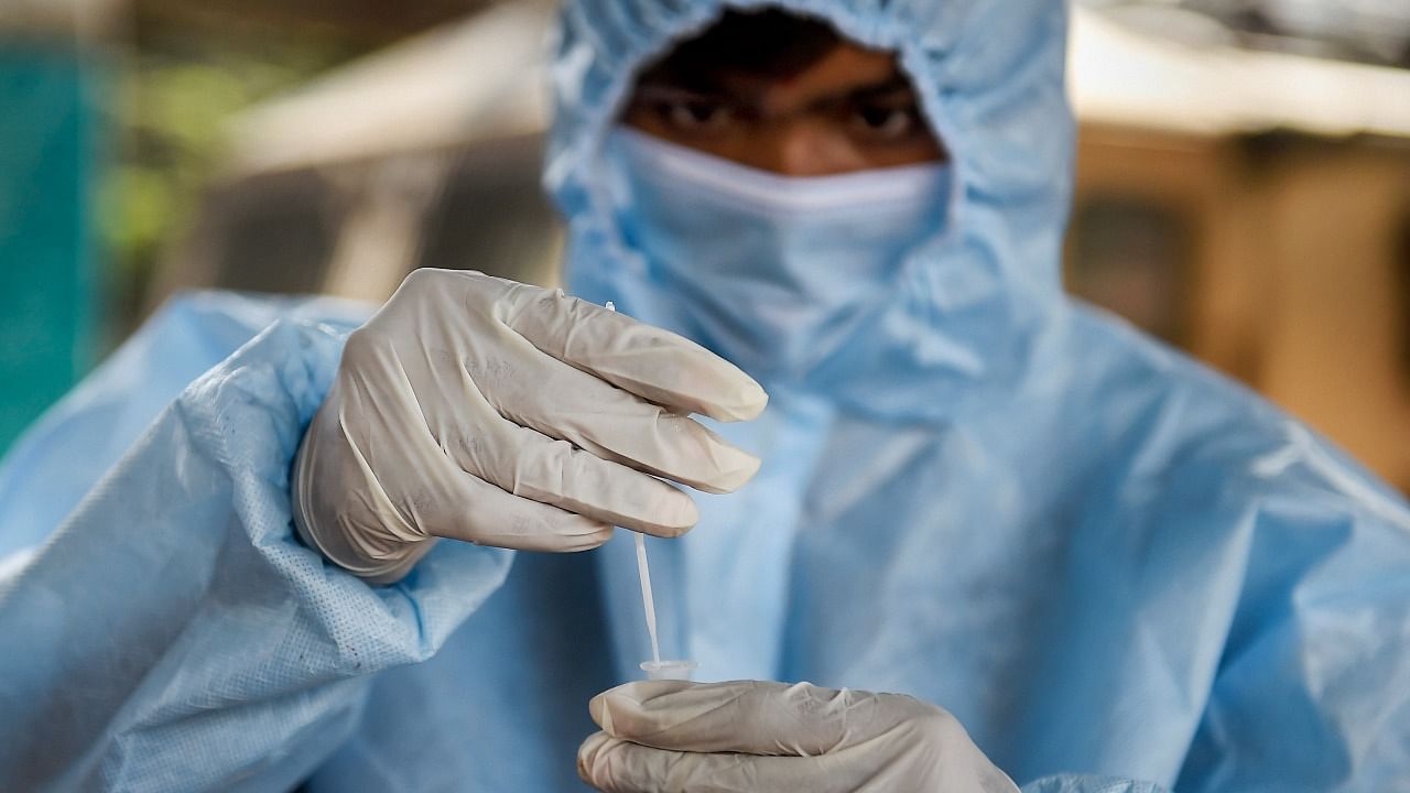 A health worker prepares to collects a swab sample of an outstation passenger for Covid-19 test, at Dadar railway station in Mumbai. Credit: PTI Photo