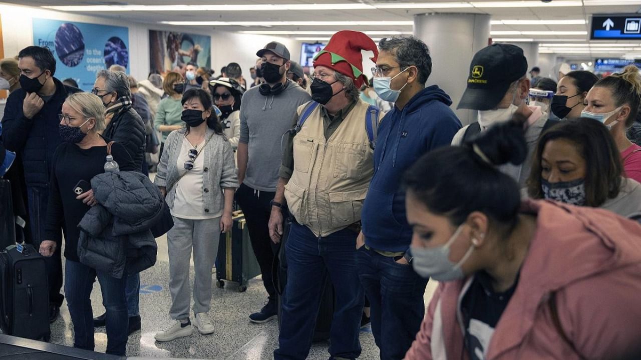 Michael Clancey wears an elf hat as he waits for his luggage after arriving at Miami International Airport from Louisville, Kentucky on December 23, 2021 in Miami, Florida. Credit: AFP Photo