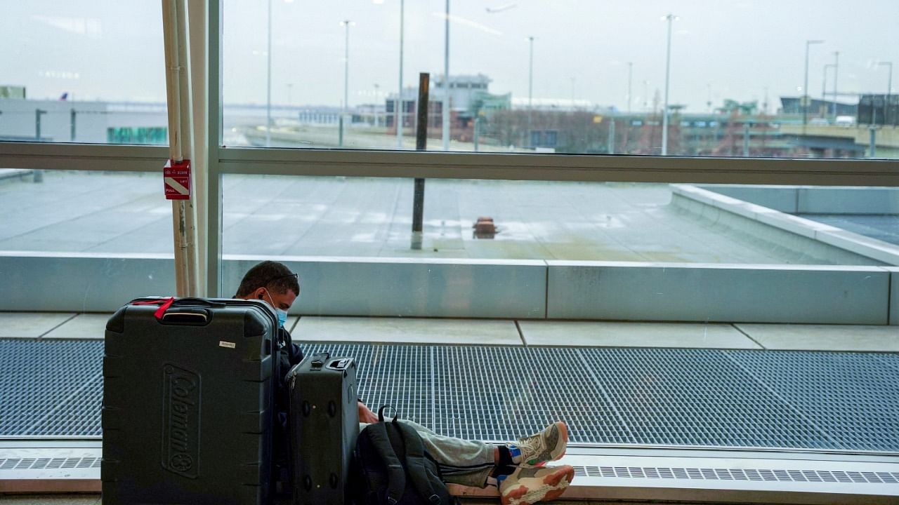 A passenger sits with luggage at John F. Kennedy International Airport after airlines announced numerous flights were canceled during the spread of the Omicron coronavirus variant on Christmas Eve in Queens, New York City. Credit: Reuters Photo