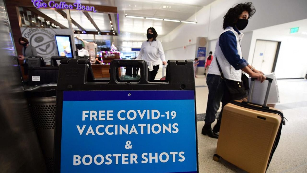 Travelers walk past a sign offering free Covid-19 vaccinations and booster shots at a pop-up clinic in the international arrivals area of Los Angeles International Airport in Los Angeles, California. Credit: AFP Photo