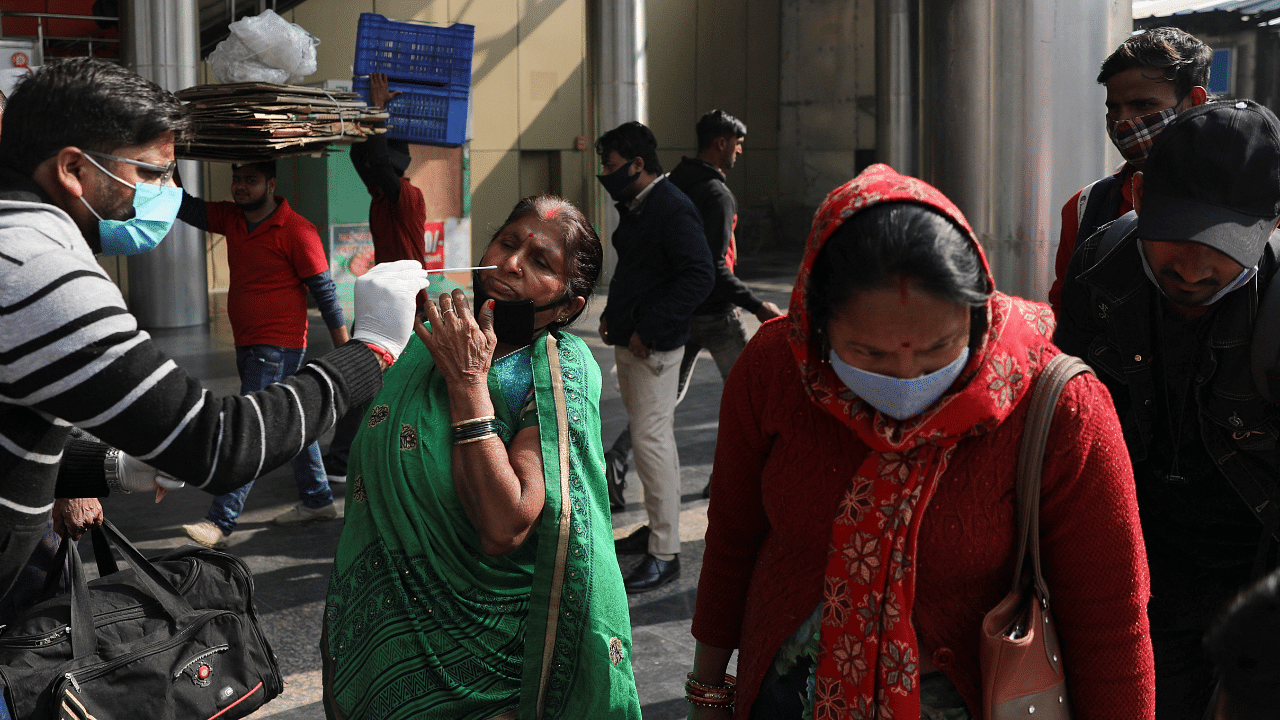 A healthcare worker collects a coronavirus disease test swab sample from a woman amidst the spread of the disease, at a railway station in New Delhi. Credit: Reuters Photo