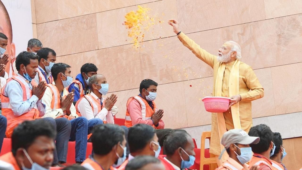 Prime Minister Narendra Modi showers flower petals on the workers involved in construction work of Kashi Vishwanath Dham Corridor in Varanasi. Credit: IANS Photo