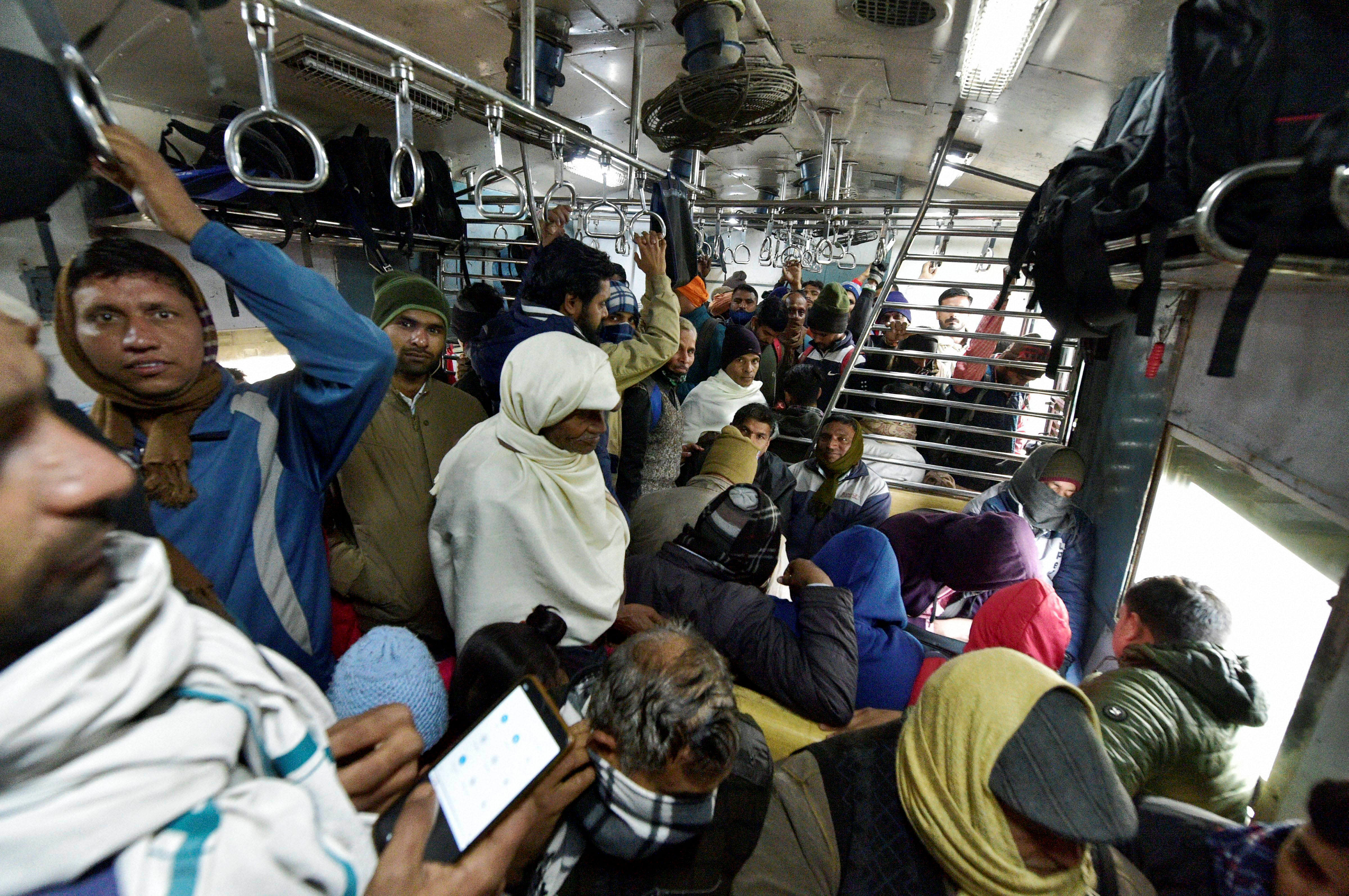 Despite concerns over Covid-19, public continues to flout mask rules and crowd an EMU train in Noida. Credit: PTI Photo