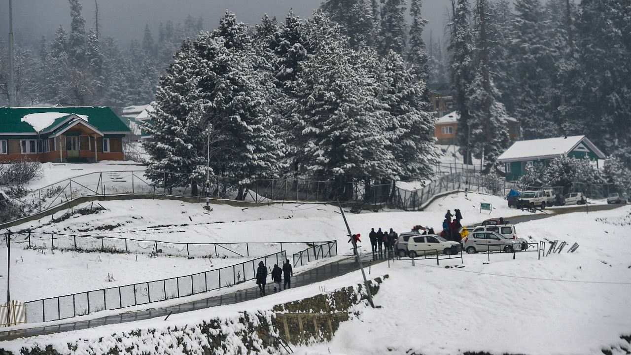 Tourists walk along a road during light snowfall at ski resort of Gulmarg in Baramulla district of north Kashmir, Thursday. Credit: PTI Photo