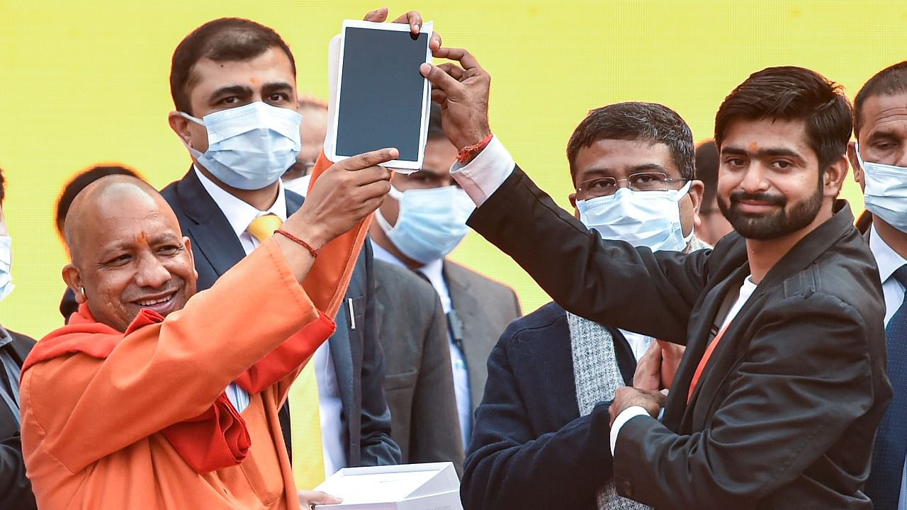 CM Yogi Adityanath distributes smartphone to a student at the Ekana Sports Stadium. Credit: PTI Photo