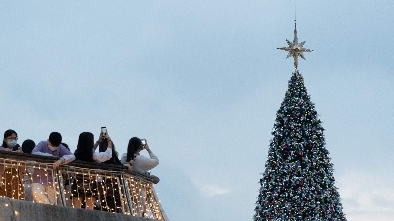 People take photos of a giant Christmas tree during Christmas at the West Kowloon cultural district in Hong Kong. Credit: AFP Photo