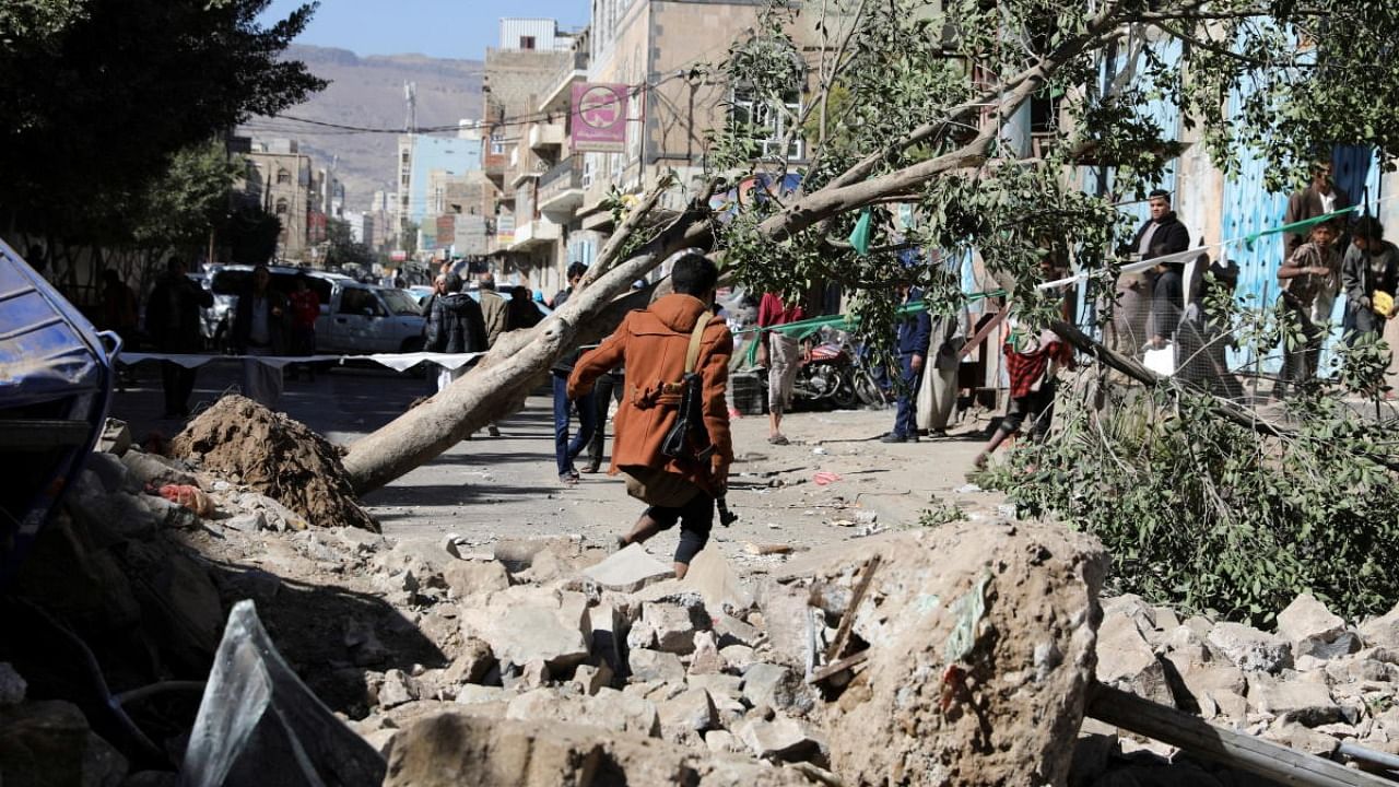 An armed man walks at the site of a Saudi-led air strike in Sanaa, Yemen. Credit: Reuters Photo