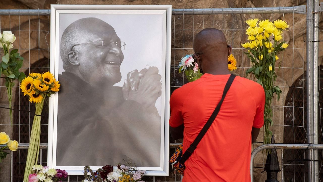 A mourner brings flowers to St. Georges Cathedral, where a Wall of Remembrance for South African anti-apartheid icon Desmond Tutu has been set up. Credit: AFP Photo