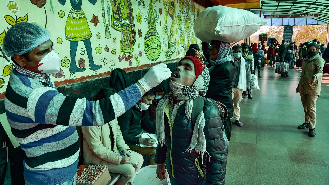 A health official takes a swab sample for Covid-19 testing at New Delhi Railway station amid concern over rising Omicron cases, in New Delhi, Monday. Credit: PTI Photo
