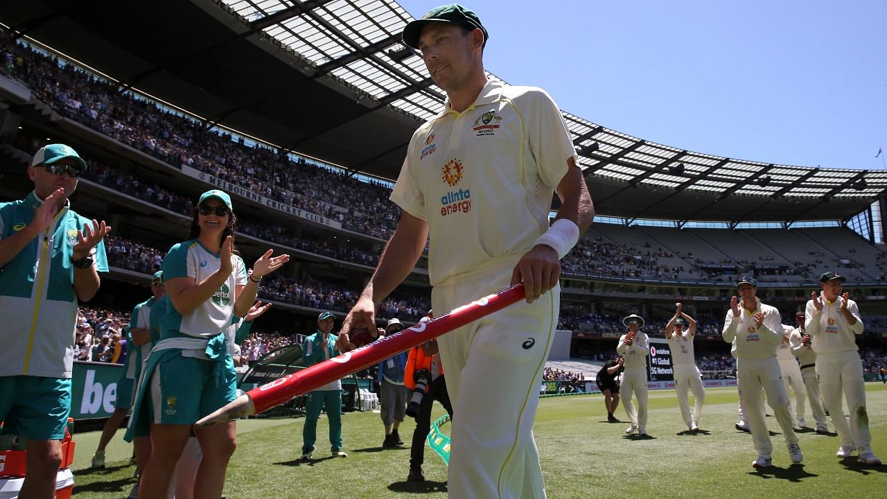 Australia's Scott Boland, center, holds holds a stump after taking 6 wickets against England in their win on the third day of their cricket test match in Melbourne, Australia, Tuesday, December 28, 2021. Credit: AP/PTI Photo