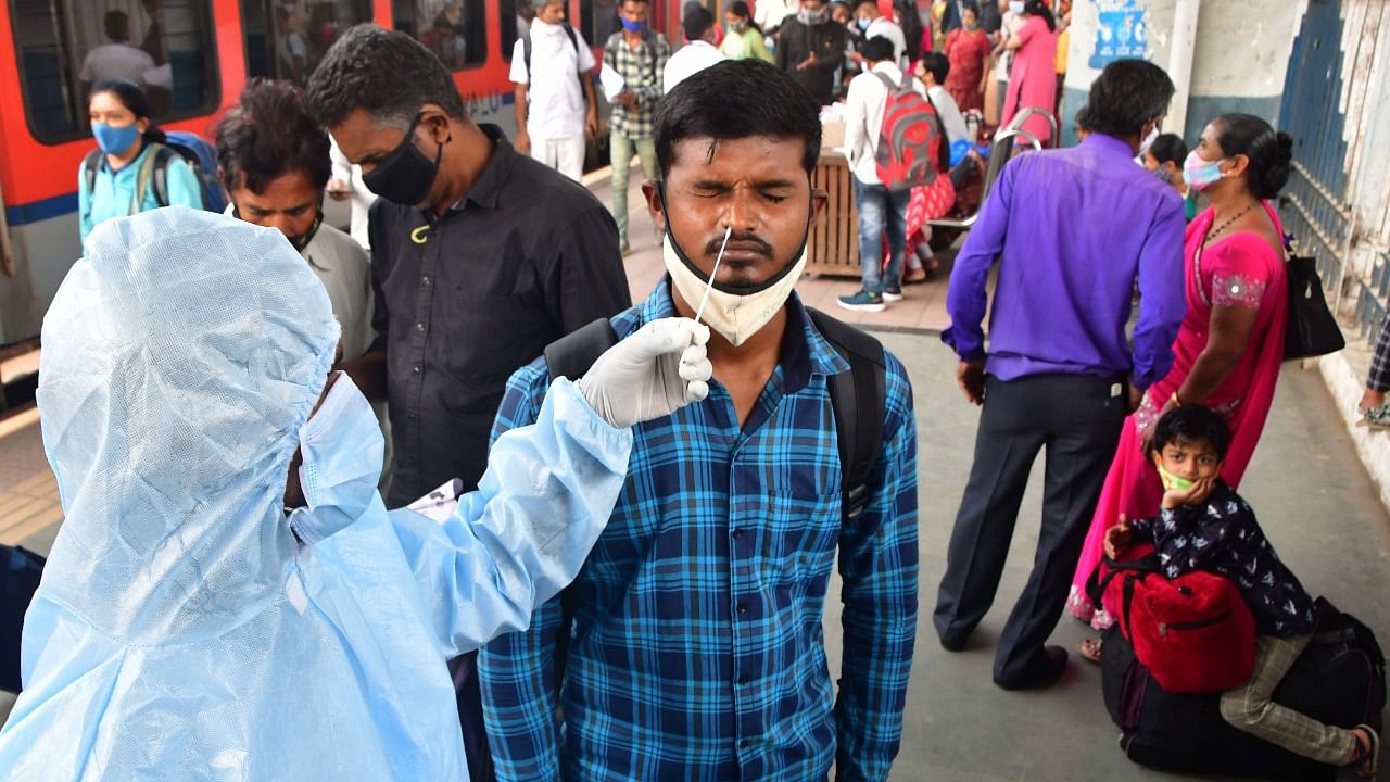  A BMC health worker collects swab sample of an outstation passenger for Covid-19 test, at Dadar railway station, in Mumbai, Saturday, December 18, 2021. Credit: PTI Photo