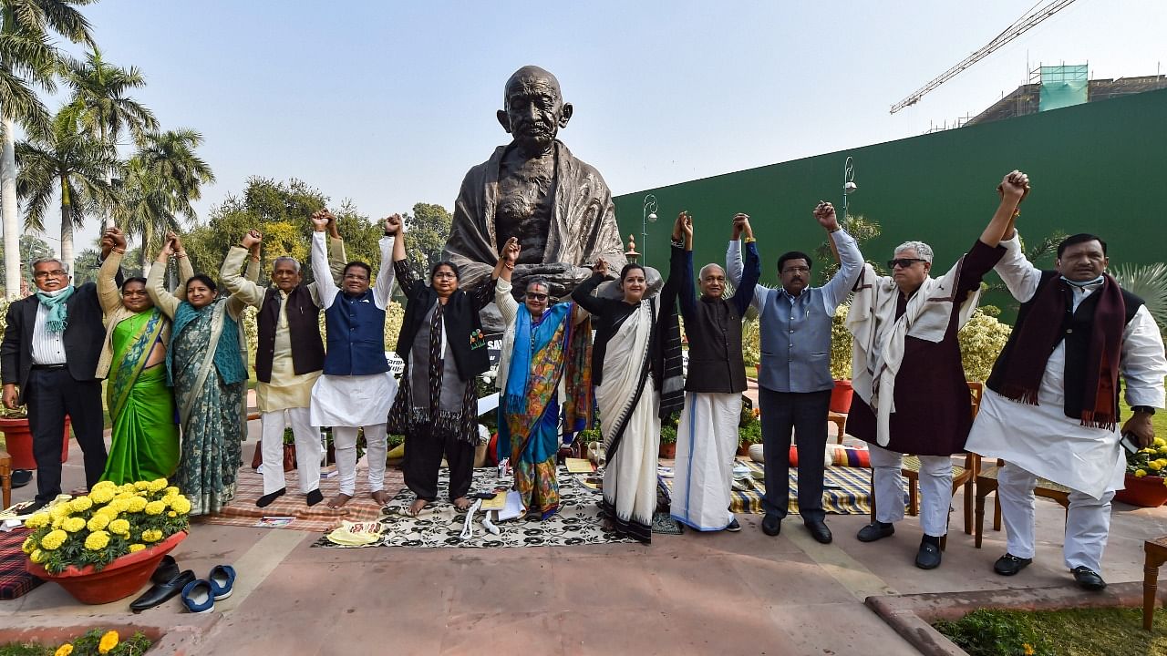 Suspended Rajya Sabha MPs stage a protest near the statue of Mahatma Gandhi demanding revocation of their suspension, at Parliament House premises in New Delhi, Wednesday, December 22, 2021 Credit: PTI File Photo