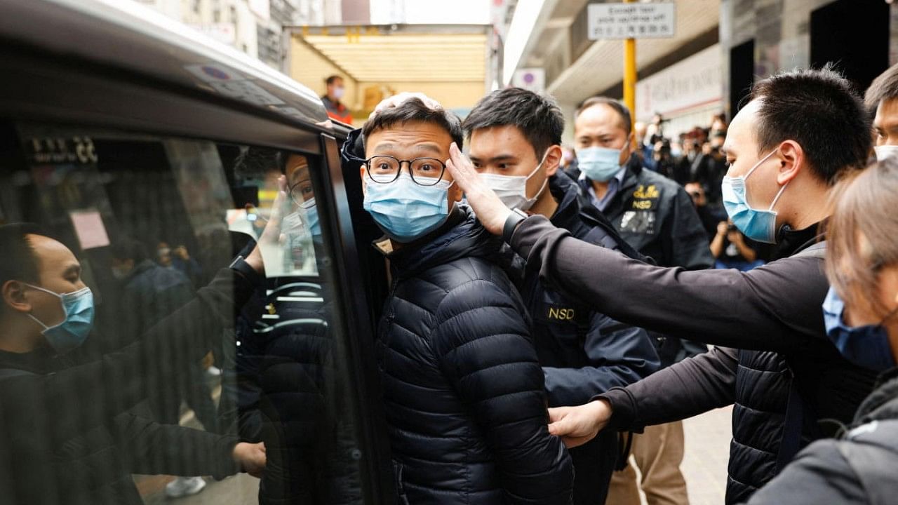 Stand News acting chief editor Patrick Lam is escorted by police as they leave after the police searched his office in Hong Kong. Credit: Reuters Photo