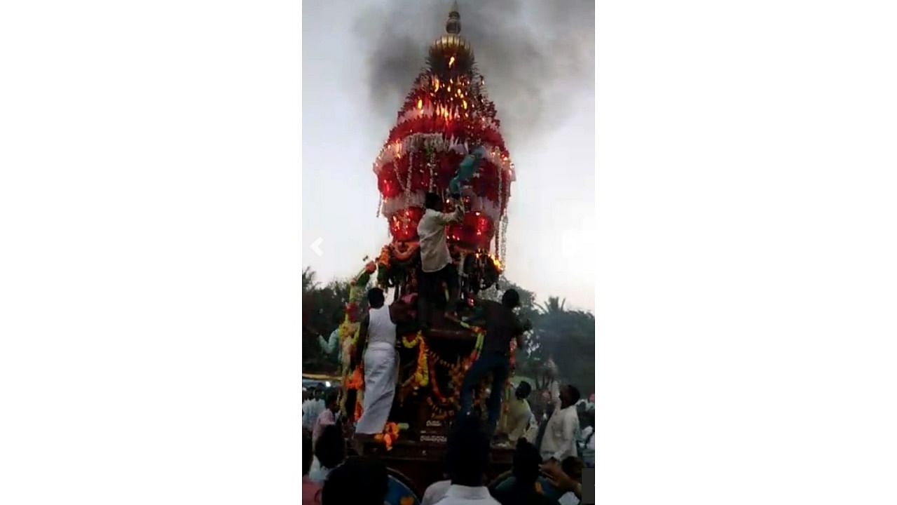 Devotees douse the fire that engulfed a chariot at Ramdurg taluk of Belagavi district on Thursday. Credit: Special Arrangement