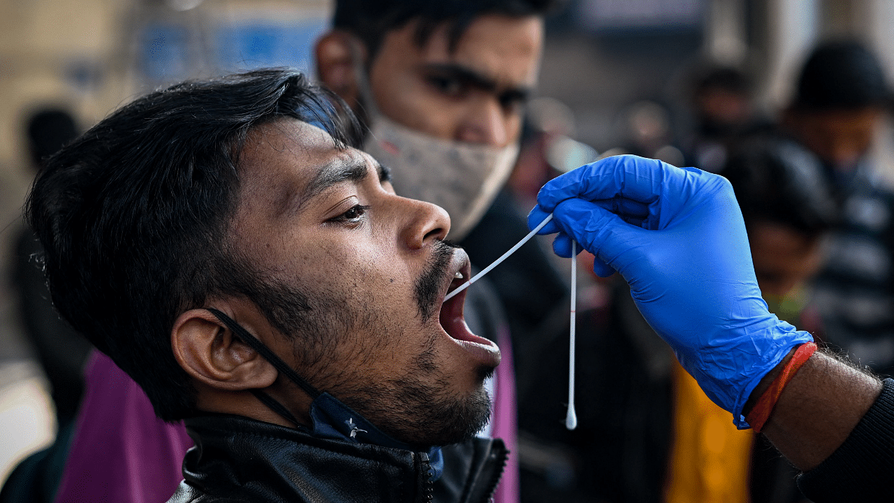 A health worker performs Covid-19 coronavirus screening of passengers at a railway station in New Delhi. Credit: AFP Photo