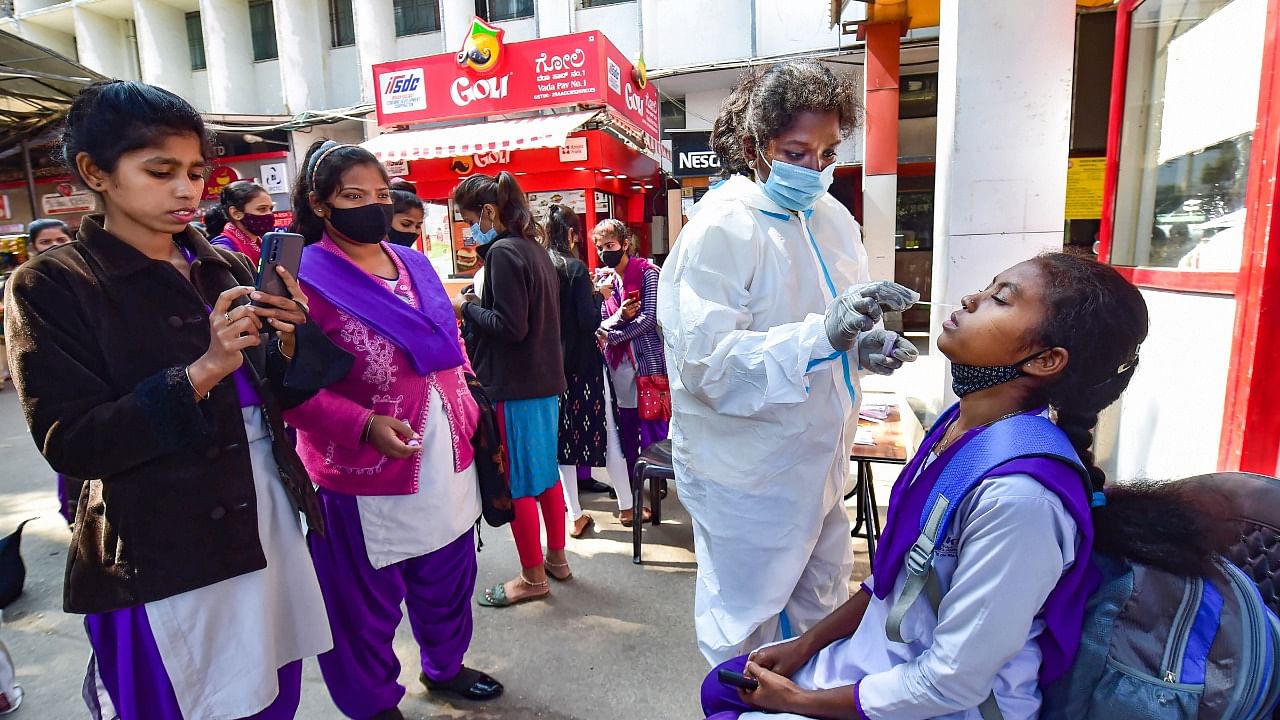 A health worker conducts Covid-19 testing of commuters as 'Omicron' cases cases rise in India, at KSR railway station in Bengaluru. Credit: PTI Photo