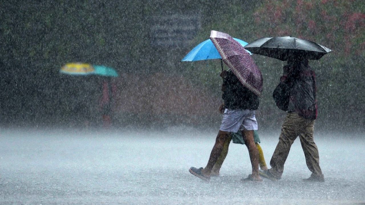 Commuters make their way through a street during a heavy rain shower in Chennai. Credit: AFP Photo