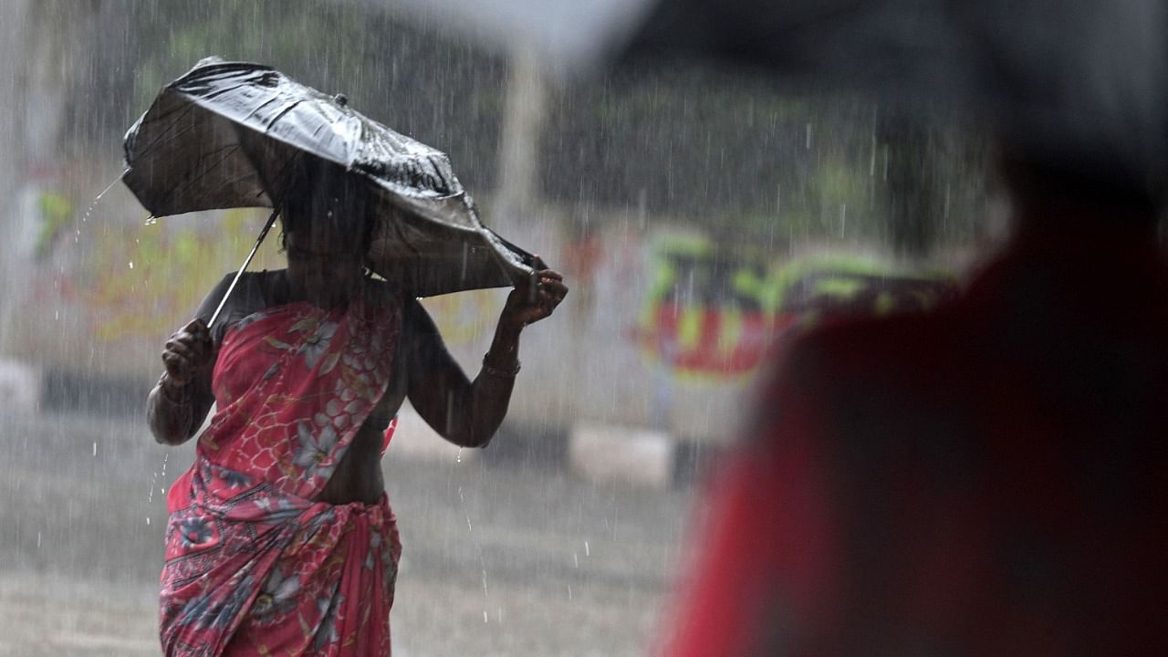 A commuter struggles to hold her umbrella during a heavy rain shower in Chennai on December 30, 2021. Credit: AFP Photo