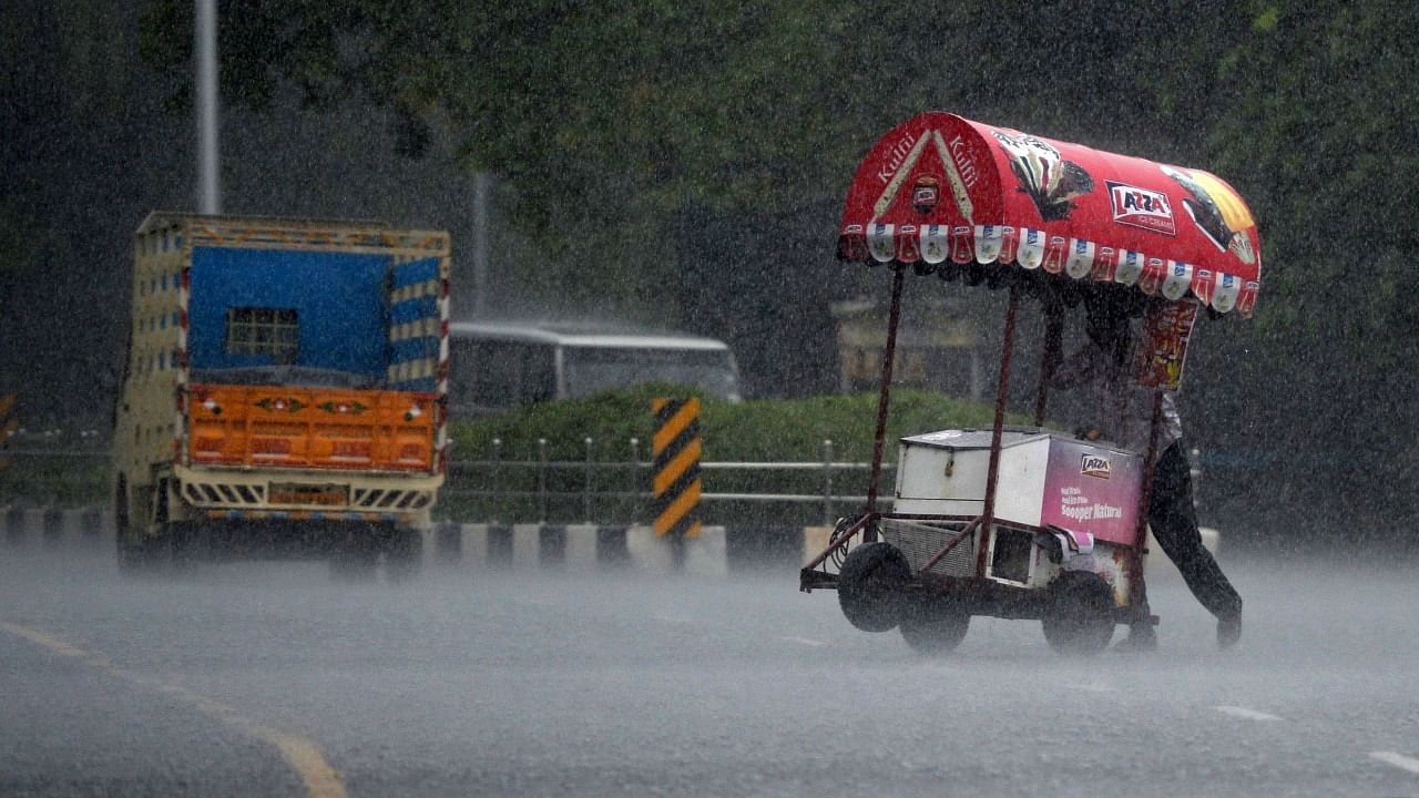 An ice cream vendor pushes his cart through a street during a heavy rain shower in Chennai on December 30, 2021. Credit: AFP Photo