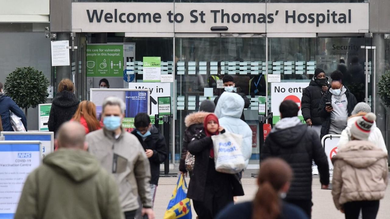 People, some wearing face coverings to combat the spread of Covid-19, arrive at, and depart from, St Thomas' hospital in central London. Credit: AFP Photo