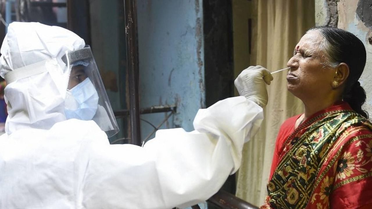 A health worker collects a swab sample of an elderly resident of Dharavi. Credit: PTI Photo