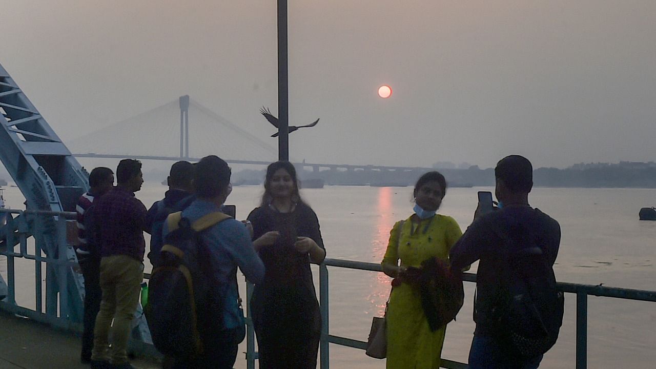 People are silhouetted against the setting sun over the Ganga river on the last day of 2021, in Kolkata, Friday, December 31, 2021. Credit: PTI Photo