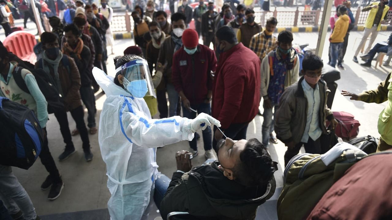  A health worker collects swab samples of passengers to conduct COVID-19 test, amid concern over rise in Omicron virus variant cases, at the Anand Vihar railway station near New Delh. Credit: PTI Photo