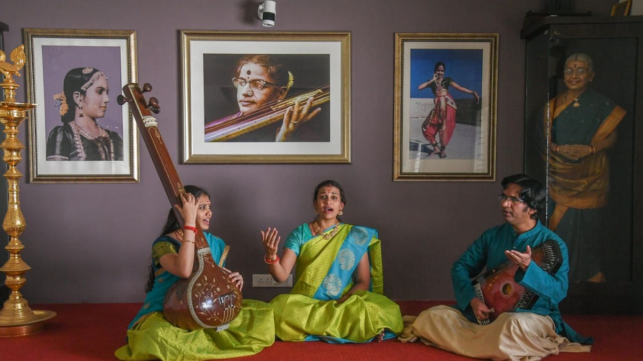 S Aishwarya (centre) and S Saundarya, great granddaughters of M S Subbulakshmi, are learning Hindustani classical music from Omkarnath Havaldar. This picture was shot at their practice room, which has a portrait of the legend in the background. Credit: DH Photo