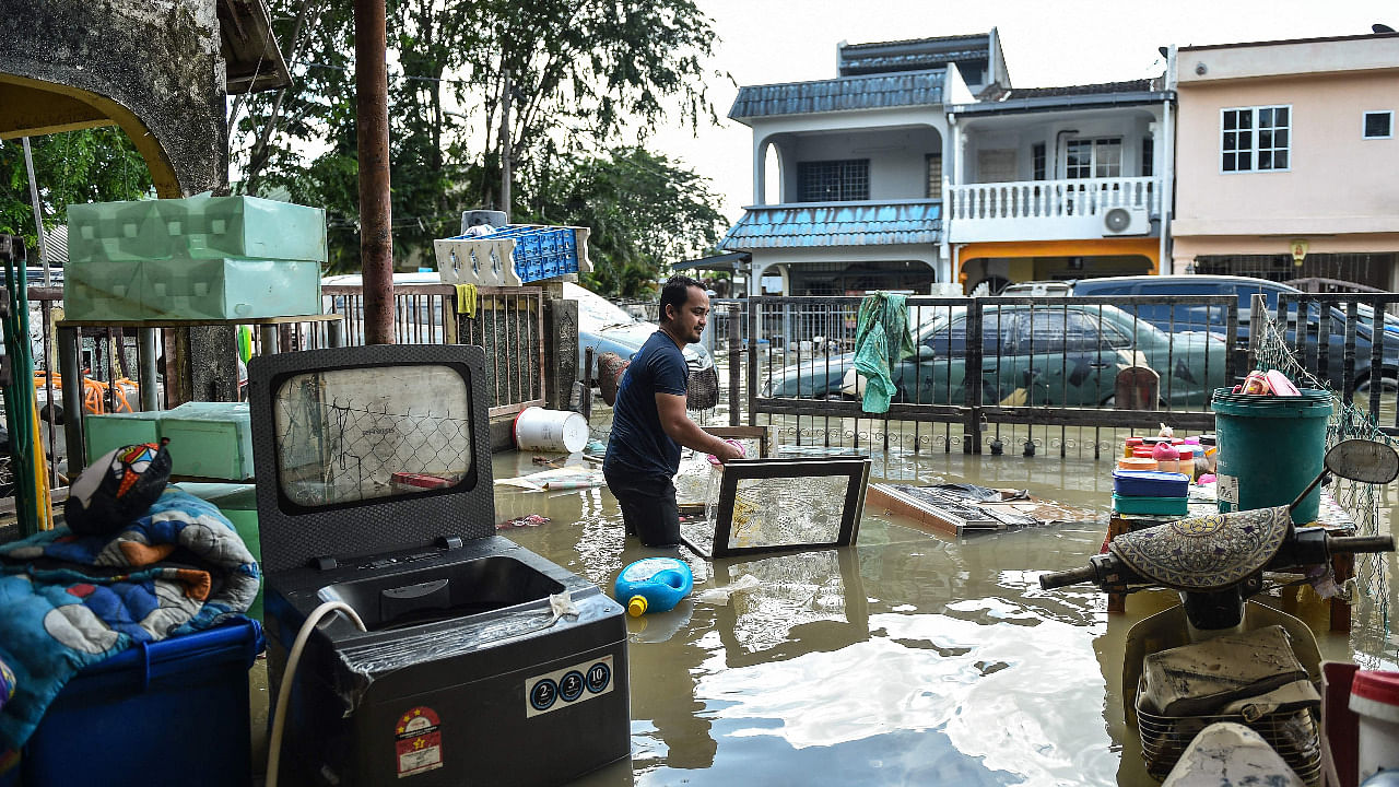 A man salvages items from his house after it was submerged in floodwaters in Shah Alam, Selangor. Credit: AFP File Photo