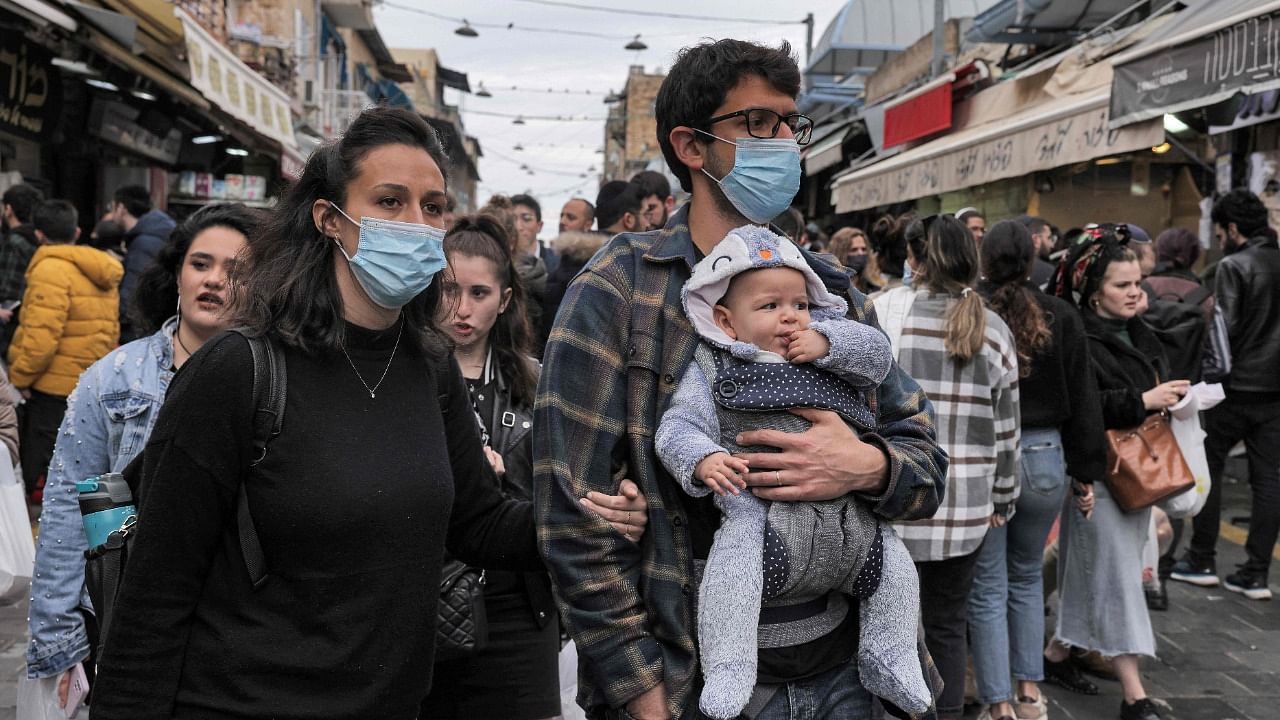 People wearing masks due to the Covid-19 coronavirus pandemic walk at the Mahane Yehuda market in the centre of Jerusalem. Credit: AFP File Photo