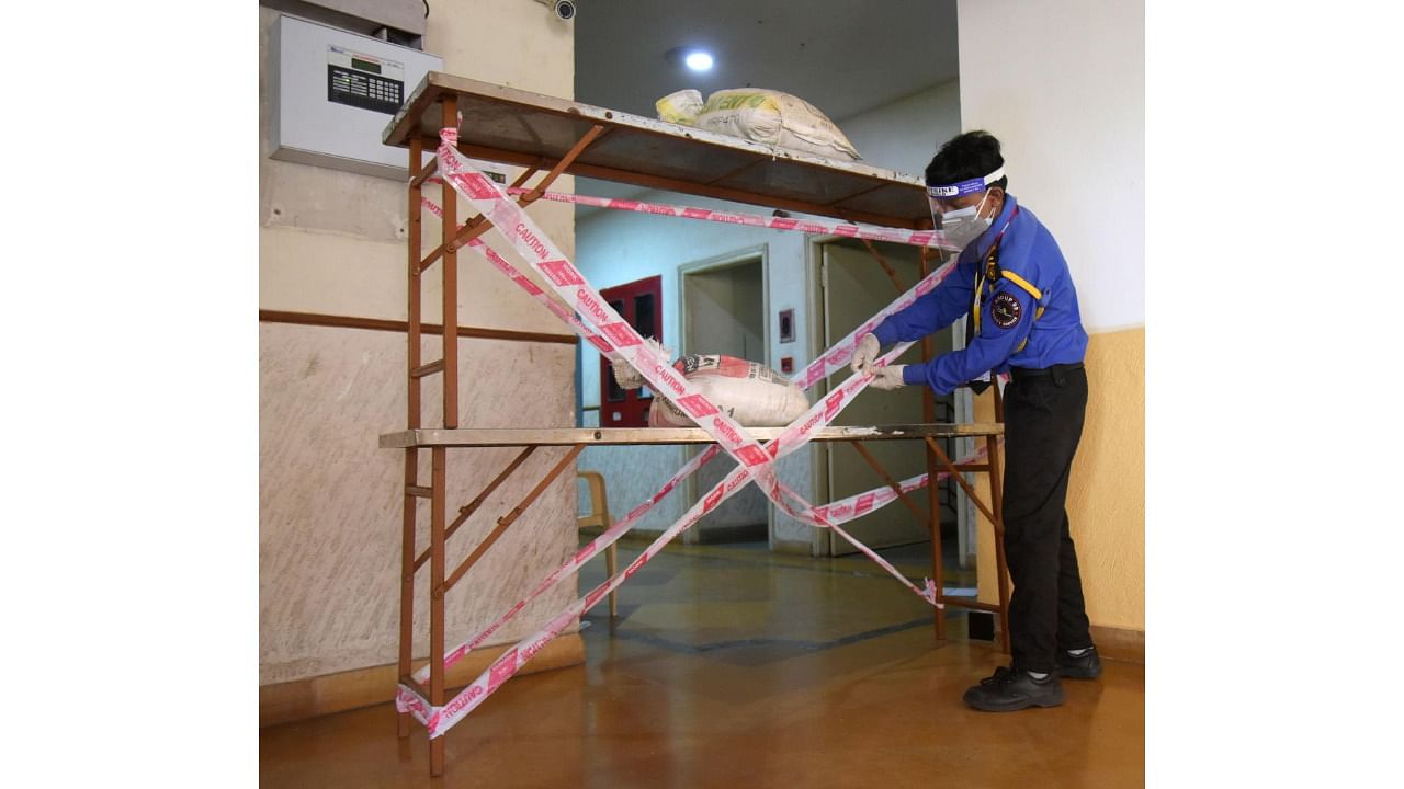 A security guard seals the entrance to an apartment complex in Mahalakshmi Layout after several of its residents tested positive for Covid-19. Credit: DH Photo
