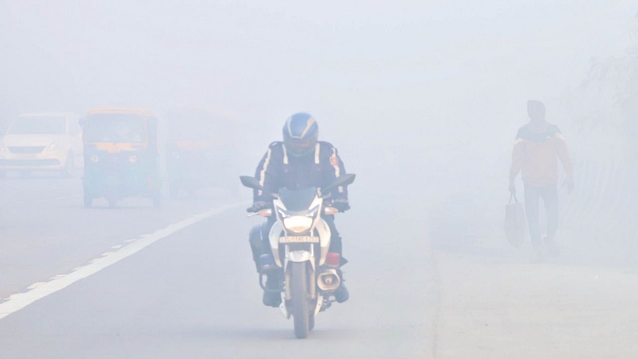 A file photo of commuters on the road amid dense fog in New Delhi. Credit: IANS Photo