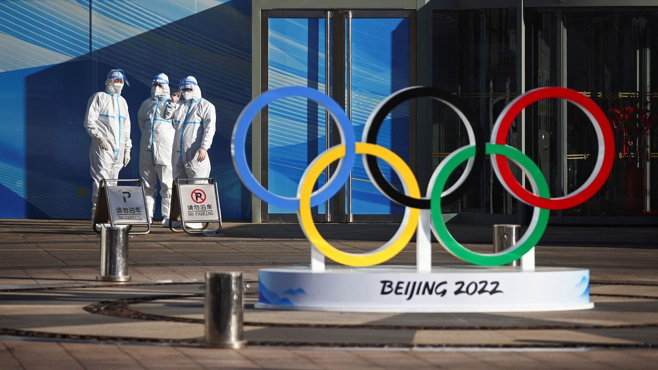 Workers in PPE stand next to the Olympic rings inside the closed loop area near the National Stadium in Beijing. Credit: Reuters Photo