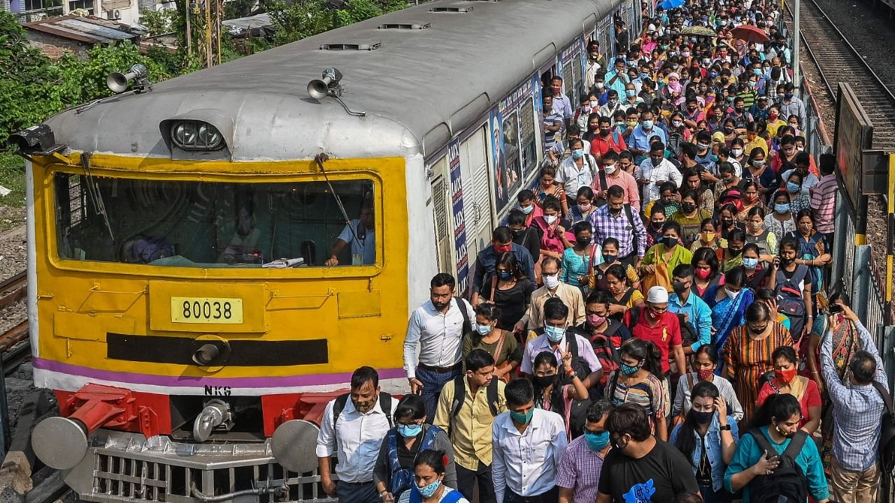 Commuters walk along a railway platform after stepping out from a suburban local train in Kolkata on November 1, 2021 as the train services resumed normalcy after plying with restrictions imposed earlier to curb the spread of Covid-19 coronavirus. Credit: AFP File Photo